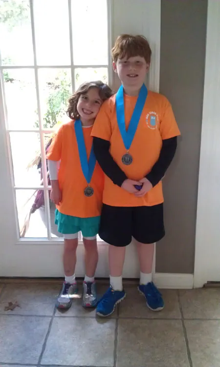 Matthew and Caroline in matching orange shirts, each wearing a race medal